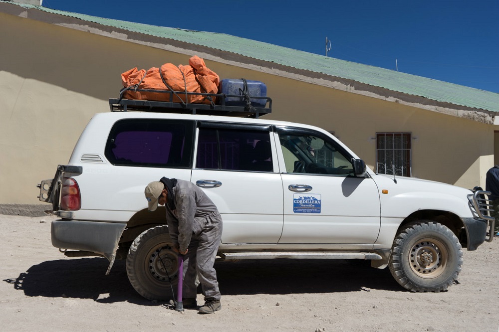 De achterband van de jeep wordt opgepompt met een fietspomp in Bolivia