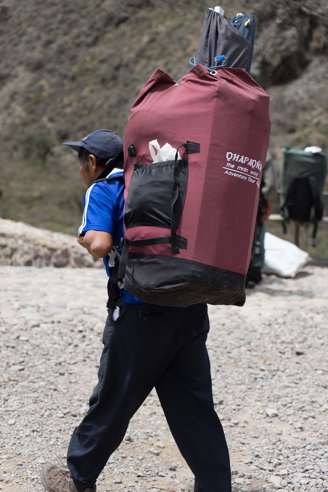 Een porter met zijn bagage onderweg op de Inca Trail in Peru